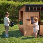 Caraway Cottage Light Brown Wooden Kids' Backyard Playhouse shown in an outdoor setting