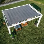 Windham Modern Steel 14 ft. x 12 ft. Pergola with Sail-Shade Canopy shown in an outdoor setting